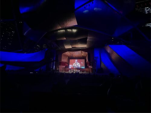 Jay Pritzker Pavillion at night with a projection of Marquis Hill playing trumpet on the screen